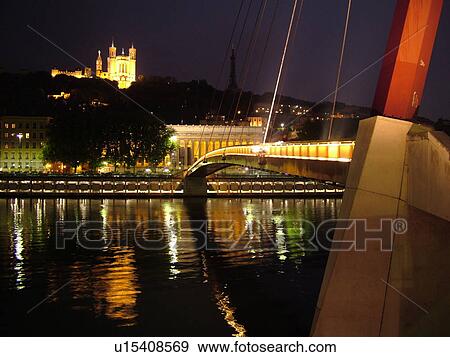 Stock Photo -  France, Lyon, Rhone-Alpes, Europe, Palais de Justice, Saone River, Basilique Notre-Dame de Fourviere, pedestrian bridge, evening, illuminated. Fotosearch
