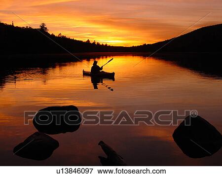 Stock Photo -  Groton, VT, Vermont, Groton State Forest, Woman kayaking on Kettle Pond at sunset. Fotosearch