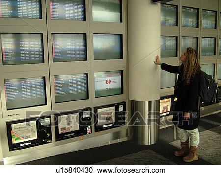 Stock Image -  Minneapolis, MN, Minnesota, Minneapolis International Airport, airport information, flight arrivals and departure monitors, airport terminal, hub, 20 year old woman looking at monitors. Fotosearch