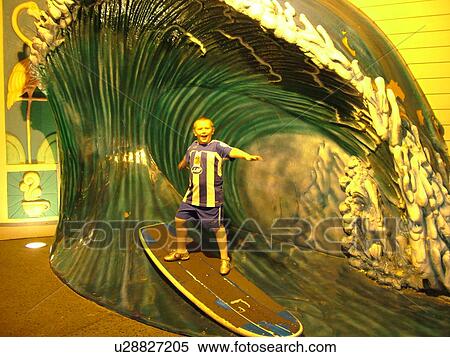 Stock Photography -  Orlando, FL, Florida, Universal Orlando Resort, Universal City Walk, evening, boy on surfboard display at surfing attraction. Fotosearch