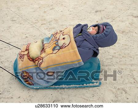 Stock Image -  Quebec City, Quebec, Canada, Winter Carnival 2006, snow, baby bundled up in plastic sled. Fotosearch