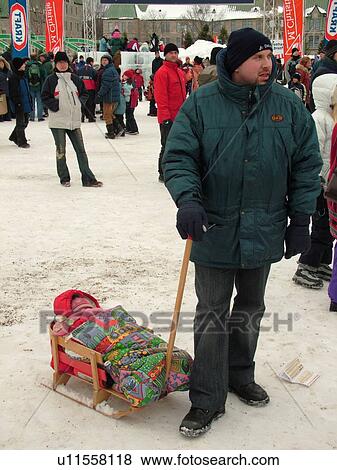 Stock Photo -  Quebec City, Quebec, Canada, Winter Carnival 2006, snow, father pulling baby bundled up in wooden sled. Fotosearch