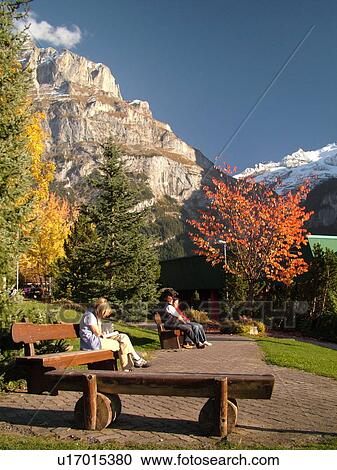 Stock Image -  Switzerland, Europe, Bern, Berne, Grindelwald, Bernese Alps, Berner Oberland, people sitting on wooden benches overlooking the mountains. Fotosearch