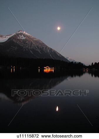 Stock Image -  Switzerland, Europe, Lenzereide, Valbella, Heidsee, Graubunden, Grisons, moonrise, mountain lake, reflection, evening. Fotosearch