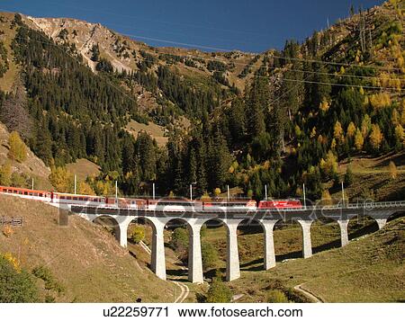 Switzerland, Europe, Sedrun, Graubunden, Grisons, railroad bridge, Matterhorn-Gotthard-Bahn Glacier Express red train View Large Photo Image Stock Image - Switzerland, Europe, Sedrun, Graubunden, Grisons, railroad bridge, Matterhorn-Gotthard-Bahn Glacier Express red train. Fotosearch