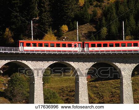 Stock Photograph -  Switzerland, Europe, Sedrun, Graubunden, Grisons, railroad bridge, Matterhorn-Gotthard-Bahn Glacier Express red train. Fotosearch