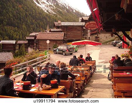 Picture -  Switzerland, Europe, valais, wallis, Val d'Anniviers, Grimentz, alpine village, Hotel Restaurant De Moiry, outdoor cafT, people eating fondue. Fotosearch