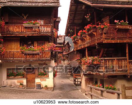 Switzerland, Europe, valais, wallis, Val d'Anniviers, Grimentz, old chalets along a narrow pedestrian street decorated with flowers View Large Photo Image Stock Image - Switzerland, Europe, valais, wallis, Val d'Anniviers, Grimentz, old chalets along a narrow pedestrian street decorated with flowers. Fotosearch