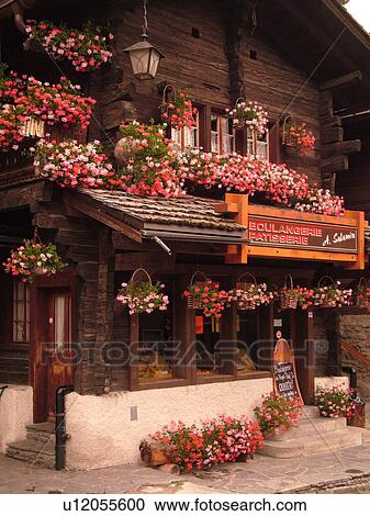 Stock Image -  Switzerland, Europe, valais, wallis, Val d'Anniviers, Grimentz, chalet, Boulangerie, Patisserie decorated with pink and red geraniums. Fotosearch