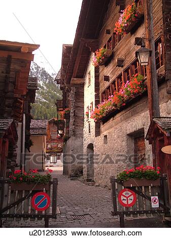 Stock Image -  Switzerland, Europe, valais, wallis, Val d'Anniviers, Grimentz, old chalets along a narrow pedestrian street, gate, no motor vehicles. Fotosearch