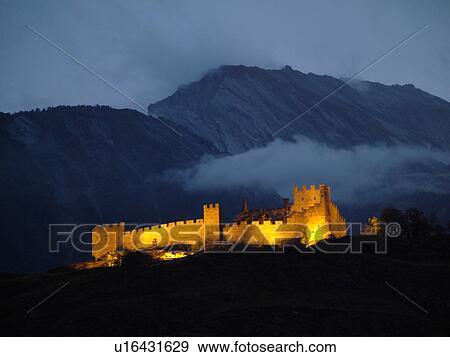 Stock Photo -  Switzerland, Europe, valais, wallis, Sion, Rhone Valley, Fendant Wine Region, ChGteau de Tourbillon, illuminated, evening, alps. Fotosearch