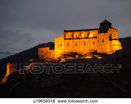 Stock Photo -  Switzerland, Europe, valais, wallis, Sion, Rhone Valley, Fendant Wine Region, Church of Notre Dame de ValFre, 11th century, illuminated, evening, alps. Fotosearch