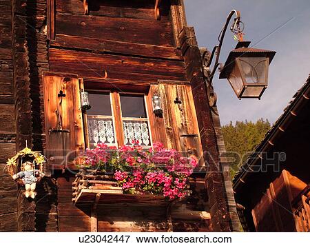 Stock Photo -  Switzerland, Europe, valais, wallis, Val d'Anniviers, Grimentz, alpine village, old wooden chalet decorated with flowers in window boxes, wooden shutters, close-up, old-fashioned street light. Fotosearch