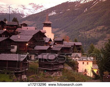 Stock Photograph -  Switzerland, Europe, valais, wallis, Val d'Anniviers, Grimentz, alpine village, church, rooftops, sunset, snow-capped mountain peaks. Fotosearch