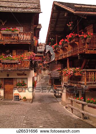Switzerland, Europe, valais, wallis, Val d'Anniviers, Grimentz, old chalets along a narrow pedestrian street decorated with flowers View Large Photo Image Stock Photograph - Switzerland, Europe, valais, wallis, Val d'Anniviers, Grimentz, old chalets along a narrow pedestrian street decorated with flowers. Fotosearch