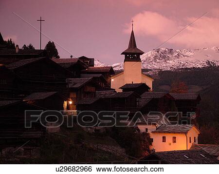 Stock Photograph -  Switzerland, Europe, valais, wallis, Val d'Anniviers, Grimentz, alpine village, church, rooftops, sunset, snow-capped mountain peaks. Fotosearch