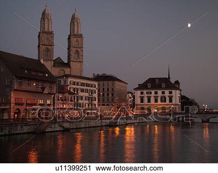 Stock Image -  Switzerland, Europe, Zurich, Zuerich, Limmat River, Grossmunster Cathedral, Limmatquai, evening. Fotosearch