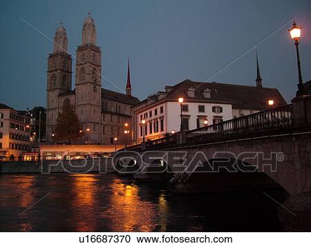 Stock Image -  Switzerland, Europe, Zurich, Zuerich, Limmat River, Grossmunster Cathedral, Limmatquai, Munster Brucke, evening. Fotosearch