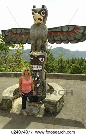 British Columbia, Canada, Vancouver Island, Woman posing next to Totem pole along Trans Canada Highway View Large Photo Image Stock Photo - British Columbia, Canada, Vancouver Island, Woman posing next to Totem pole along Trans Canada Highway. Fotosearch