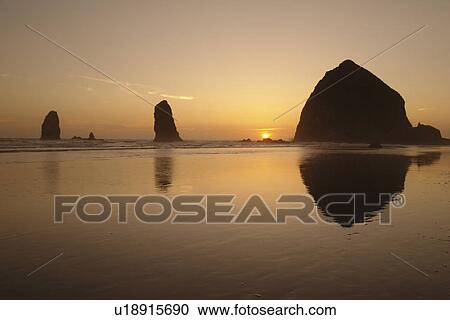 Stock Image -  Cannon Beach, OR, Oregon, Pacific Ocean, Pacific Coast Scenic Byway, Rt Route, Highway 101, Cannon Beach, Haystack Rock, reflection, sunset. Fotosearch