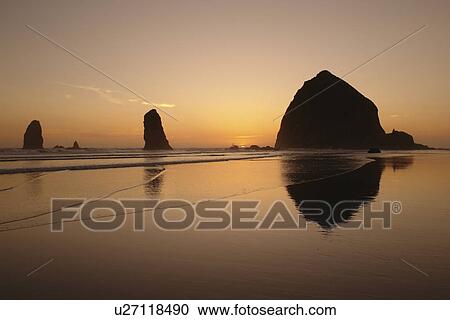 Stock Image -  Cannon Beach, OR, Oregon, Pacific Ocean, Pacific Coast Scenic Byway, Rt Route, Highway 101, Cannon Beach, Haystack Rock, reflection, sunset. Fotosearch