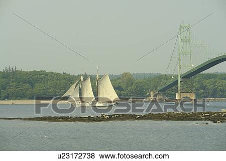Stock Photo -  Deer Isle, ME, Maine, Deer Isle Bridge, suspension bridge, schooner, tall ship, sailing vessel, island, waterway. Fotosearch