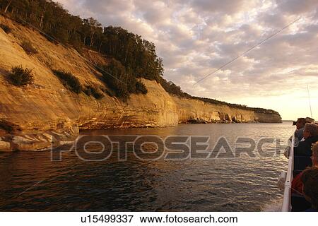 Stock Photo -  Munsing, MI, Michigan, Upper Peninsula, Lake Superior, Pictured Rocks Boat Cruise, Pictured Rocks National Lakeshore, sunset, passengers, open deck. Fotosearch