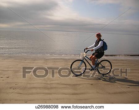 Stock Photo -  woman biking on the beach, Hilton Head Island, Low Country, South Carolina, SC, Atlantic Ocean. Fotosearch