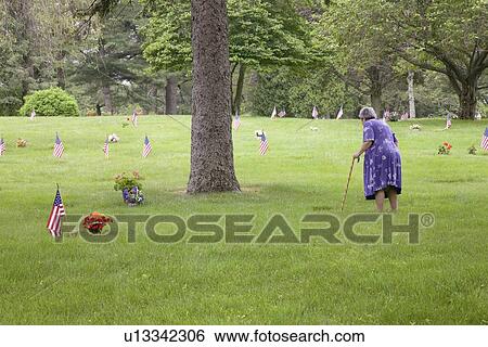 Stock Photograph - Woman in Purple Dress honors fallen soldiers, Memorial Day. Fotosearch