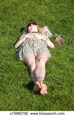 Stock Image - Young girl sleeps in grassy area of Public Gardens, Boston, MA. Fotosearch