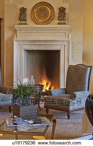 Stock Photograph - Armchair by a fireplace in luxury home. Fotosearch