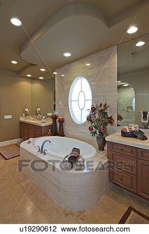 Stock Image - Bath and sink with circular window in luxurious bathroom. Fotosearch