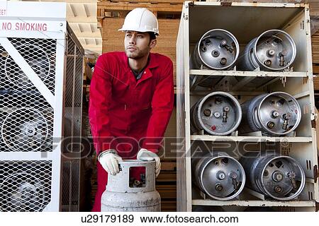 Stock Photo - Hispanic worker inspecting gas canister. Fotosearch