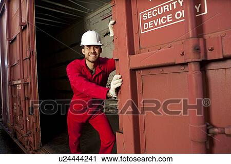 Stock Image - Hispanic worker opening industrial railway carriage. Fotosearch