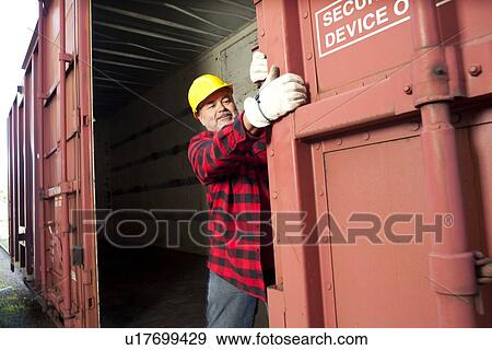 Middle Aged worker closing industrial railway carriage View Large Photo Image Stock Photo - Middle Aged worker closing industrial railway carriage. Fotosearch