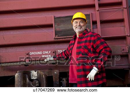 Middle Aged worker standing in industrial railway carriage View Large Photo Image Stock Photo - Middle Aged worker standing in industrial railway carriage. Fotosearch