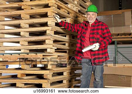 Middle aged working standing in front of wooden pallets View Large Photo Image Stock Image - Middle aged working standing in front of wooden pallets. Fotosearch