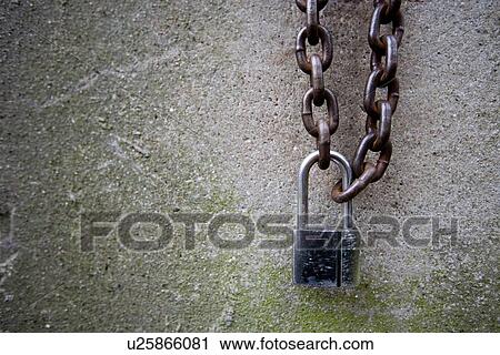 Stock Image - Padlock and chain against stone wall. Fotosearch