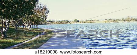 Stock Photo - Scenic view of walkway beside calm lake. Fotosearch