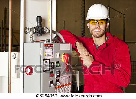 Technician standing next to electrical unit View Large Photo Image Stock Photo - Technician standing next to electrical unit. Fotosearch