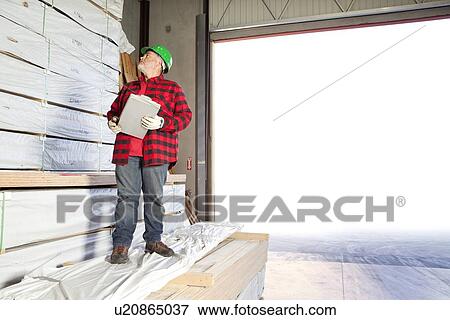 Stock Photo - Worker inspecting wood ready for distribution. Fotosearch