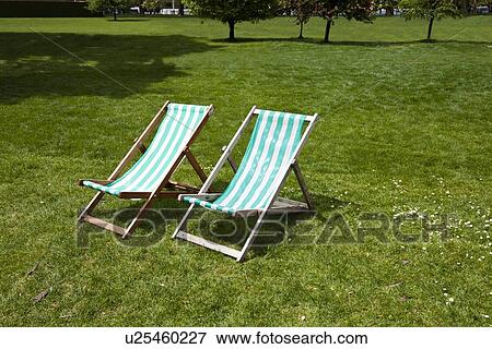 Two deck chairs in a park View Large Photo Image Stock Photo - Two deck chairs in a park. Fotosearch