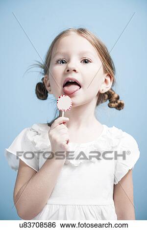 Young girl licking lollypop View Large Photo Image Stock Photograph - Young girl licking lollypop . Fotosearch