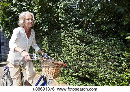 Active senior woman riding bicycle in backyard View Large Photo Image Stock Photograph - Active senior woman riding bicycle in backyard. Fotosearch