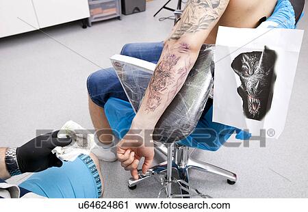Artist tattooing man's arm in tattoo parlor View Large Photo Image Stock Image - Artist tattooing man's arm in tattoo parlor. Fotosearch