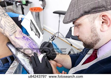 Artist tattooing man's arm in tattoo shop View Large Photo Image Stock Photo - Artist tattooing man's arm in tattoo shop. Fotosearch