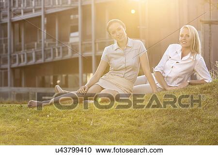 Stock Image - Beautiful young businesswomen relaxing on office lawn. Fotosearch