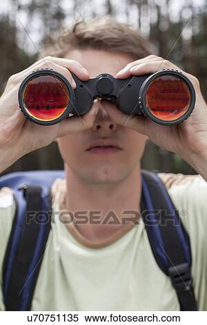 Close-up of young man looking through binoculars in forest View Large Photo Image Stock Photography - Close-up of young man looking through binoculars in forest. Fotosearch