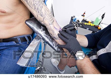 Cropped image of artist tattooing man's arm in tattoo parlor View Large Photo Image Stock Image - Cropped image of artist tattooing man's arm in tattoo parlor. Fotosearch