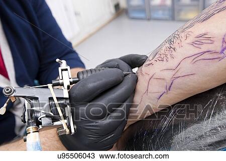 Cropped image of artist tattooing man's arm in tattoo parlor View Large Photo Image Stock Image - Cropped image of artist tattooing man's arm in tattoo parlor. Fotosearch